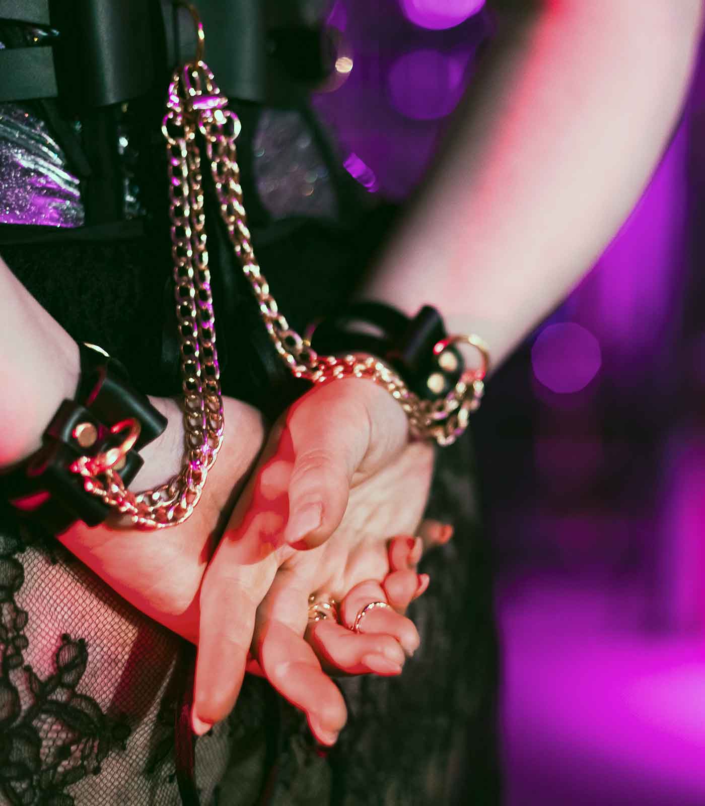 schwarze Bow Cuffs, die durch Ketten mit Karabinern mit Bow Belt verbunden sind