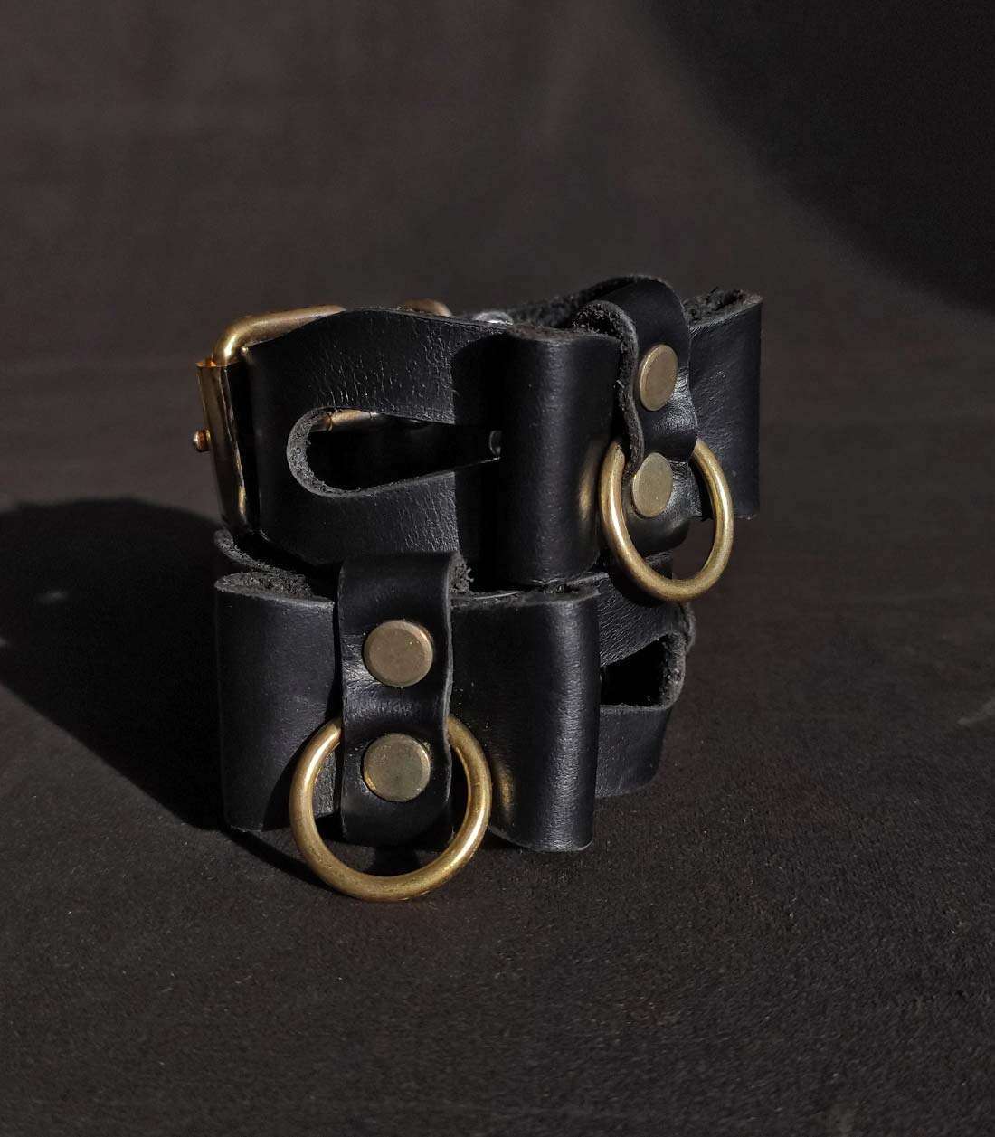 schwarze Cuffs mit Cutouts, Lederschleifen und goldener Hardware