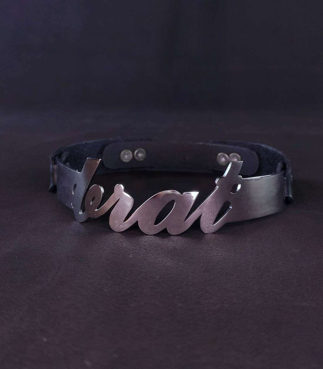 schwarzes Lederhalsband mit einem Edelstahlbügel mit "brat" Schriftzug und einem Steckverschluss über Stopper