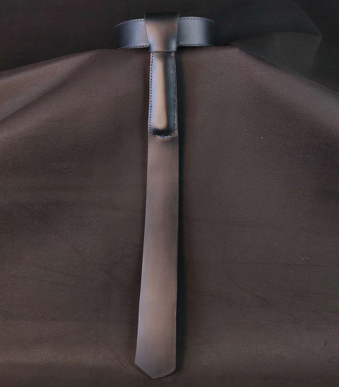 schwarzes Lederhalsband mit aufgefädeltem Krawattenzusatz, in den ein Griff eingenäht ist