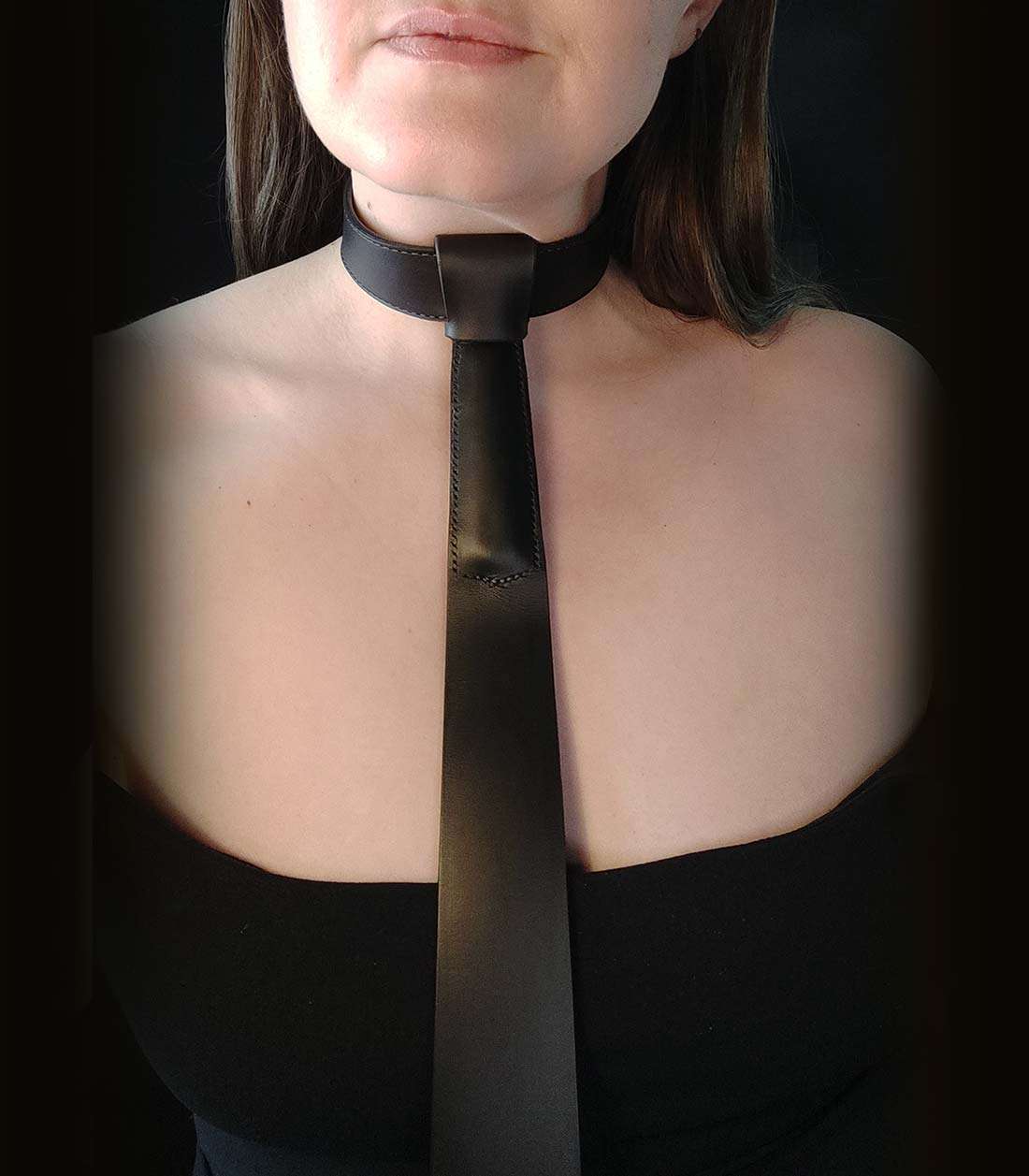 schwarzes Lederhalsband mit aufgefädeltem Krawattenzusatz, in den ein Griff eingenäht ist