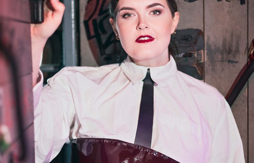 Portrait von der Gründerin von Make Me mit weißem Hemd, Impact Tie und dunkelroter Wendekorsage