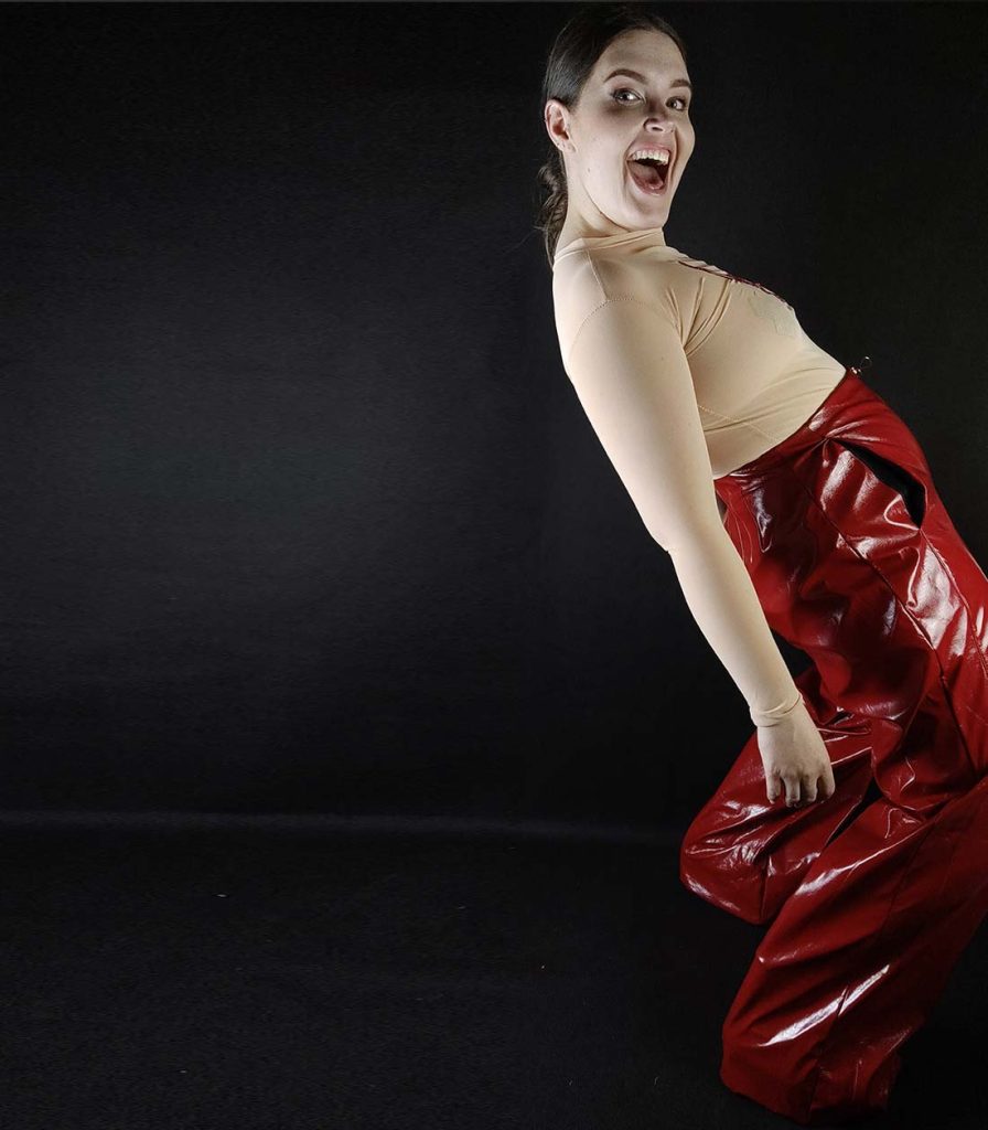 Gründerin von Make Me mit Outfit aus roter Gloss Hose und hautfarbenem Body mit Ropebunny Bestickung, die sich freut