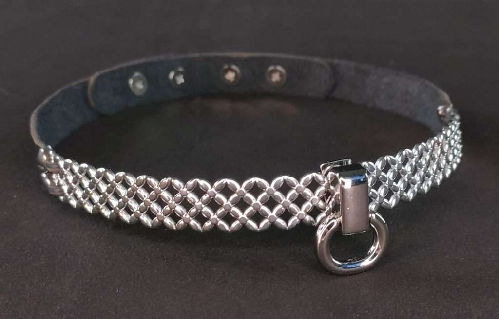 lettuce_c_detail Lederhalsband mit Edelstahlbügel mit überkreuzten Details und kleinem O-Ring, der über einen Steckverschluss mit Stoppern verschließbar ist