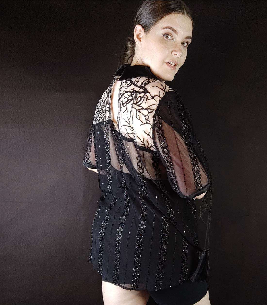 Rückseite von schwarz-transparenter Mesh Bluse mit Satinkragen und Ärmeln mit Quasten