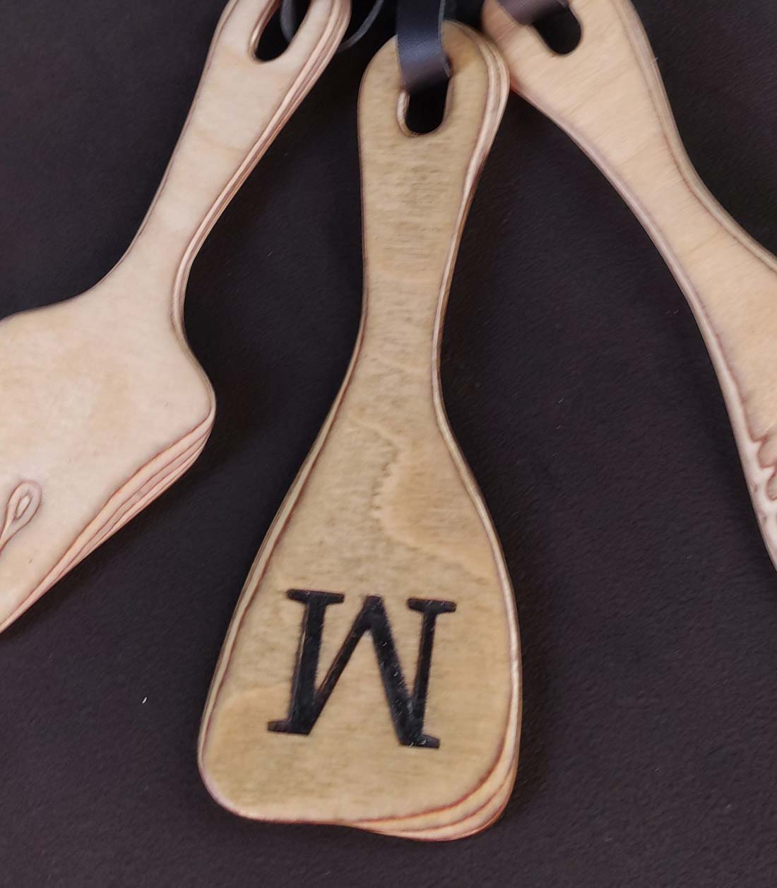 drei Mini Paddles als Set in verschiedenen Formen aus Birkenschichtholz, bei denen ein Paddle ein eingraviertes "M" hat