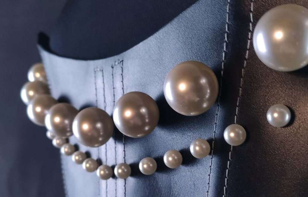 pearl_corset_detail Nahaufnahme von Kunstperlen-Nieten auf schwarzer Leder Korsage