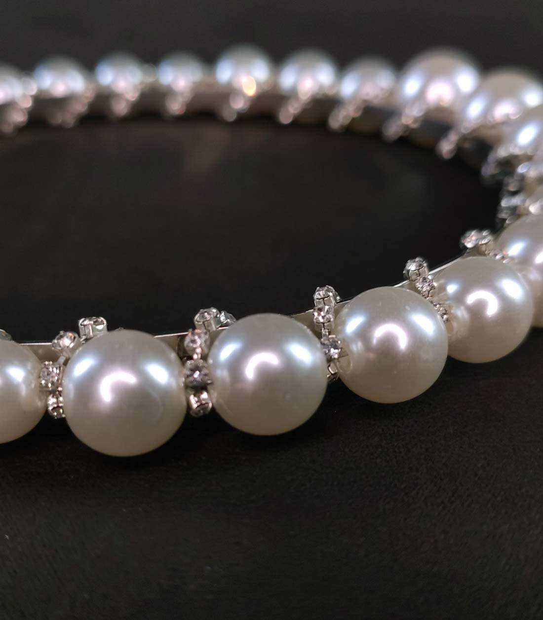 Nahaufnahme von Haarreif mit Kunstperlen und spiralförmig eingearbeitetem Glitzersteinband