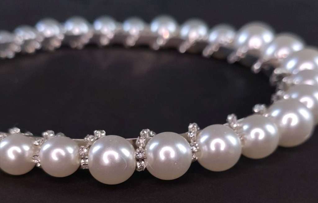 pearl_headpiece_detail Nahaufnahme von Haarreif mit Kunstperlen und spiralförmig eingearbeitetem Glitzersteinband
